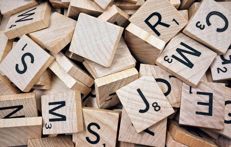A collection of wooden Scrabble tiles with letters and numbers stacked randomly.