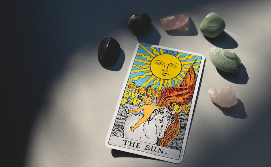 The Sun tarot card and crystals arranged on a surface with dramatic lighting and shadows.