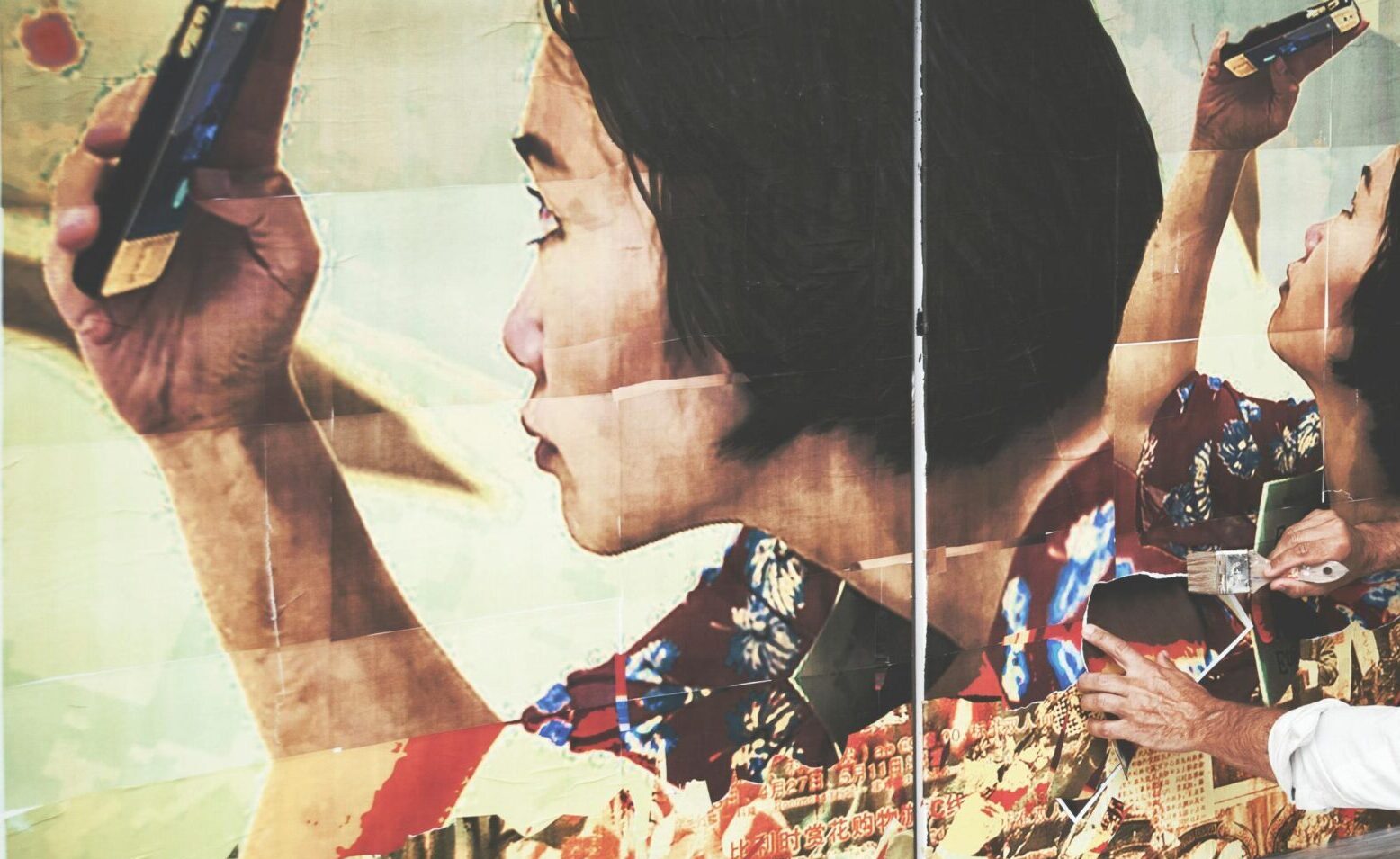 A man engaged in creating a large artistic collage indoors, capturing creativity and focus.