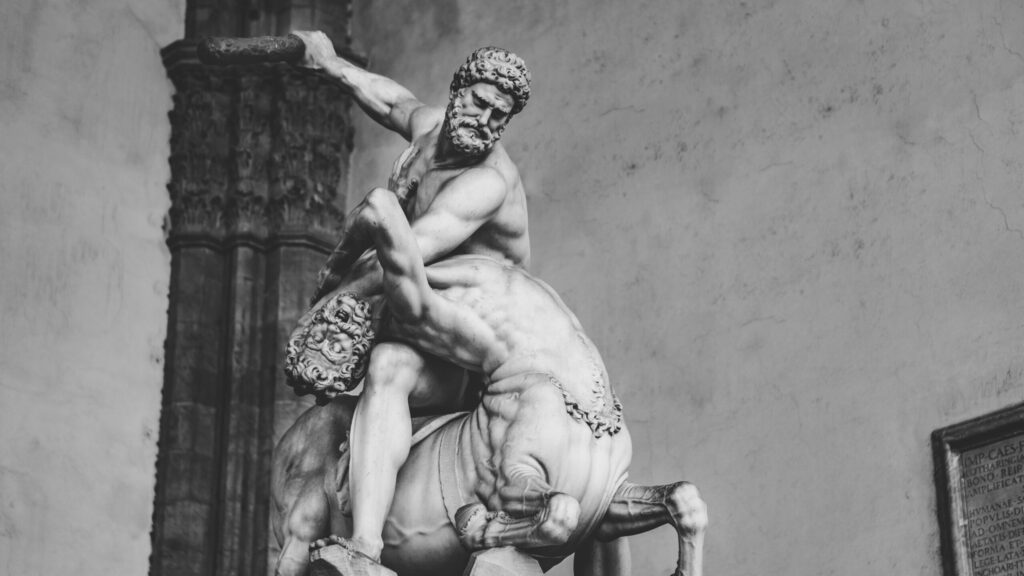 Black and white photo of a detailed marble sculpture of Hercules fighting a centaur in Tuscany, Italy.